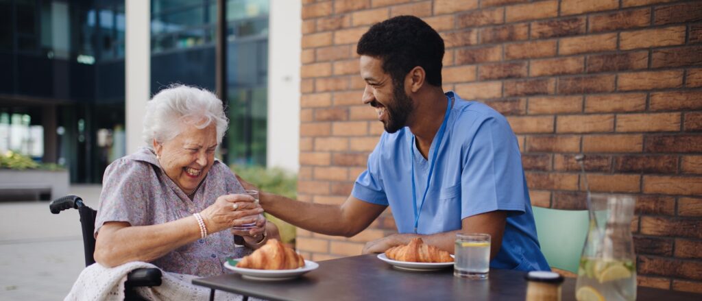 Caregiver having breakfast with his client at cafe.